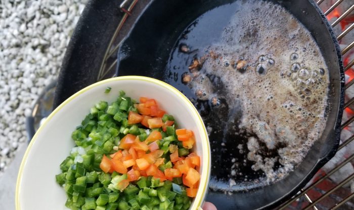 cooking up aromatics and vegetables in an iron skillet on the Weber grill 