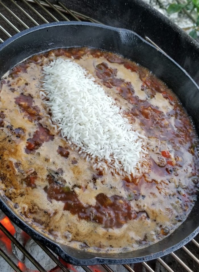 adding rice in seafood paella dish